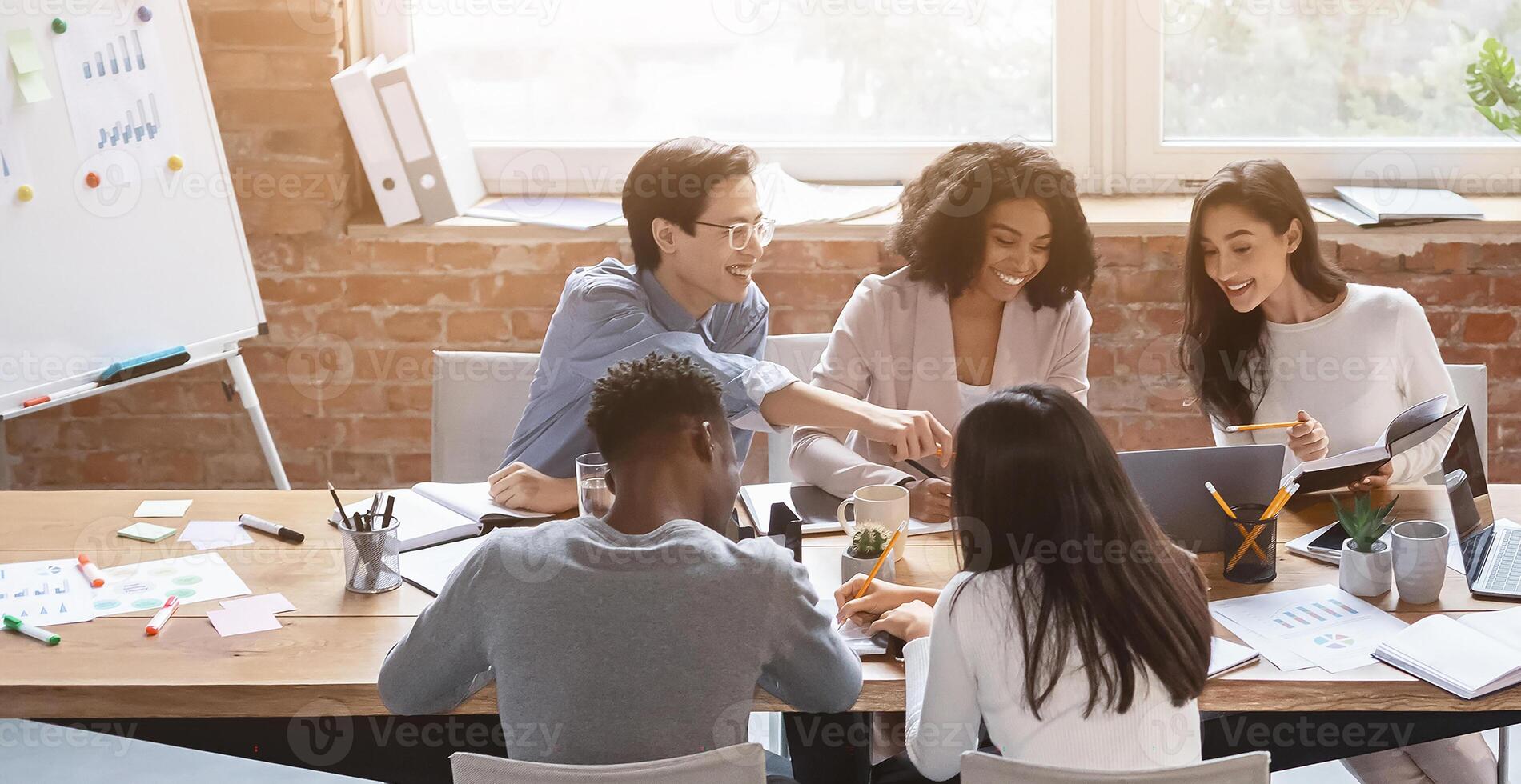Friendly multiethnic business team sitting around table, having meeting in office photo