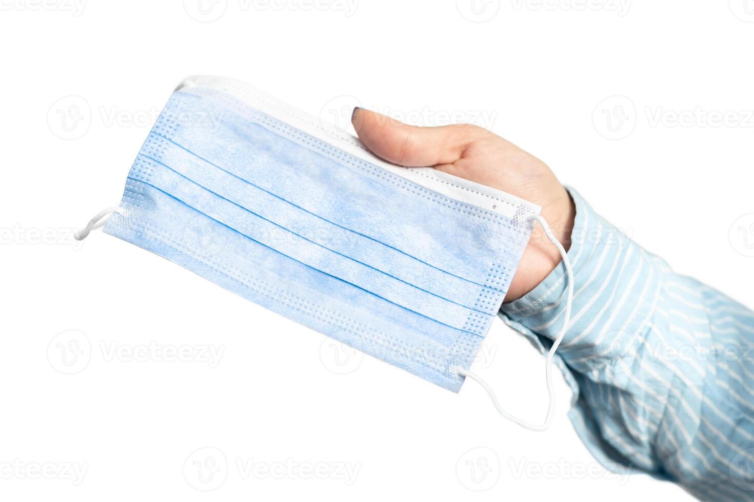 Female Hand Offering To Wear Mask To Prevent Corona Virus Spreading Over White Background. Cropped, Selective Focus photo