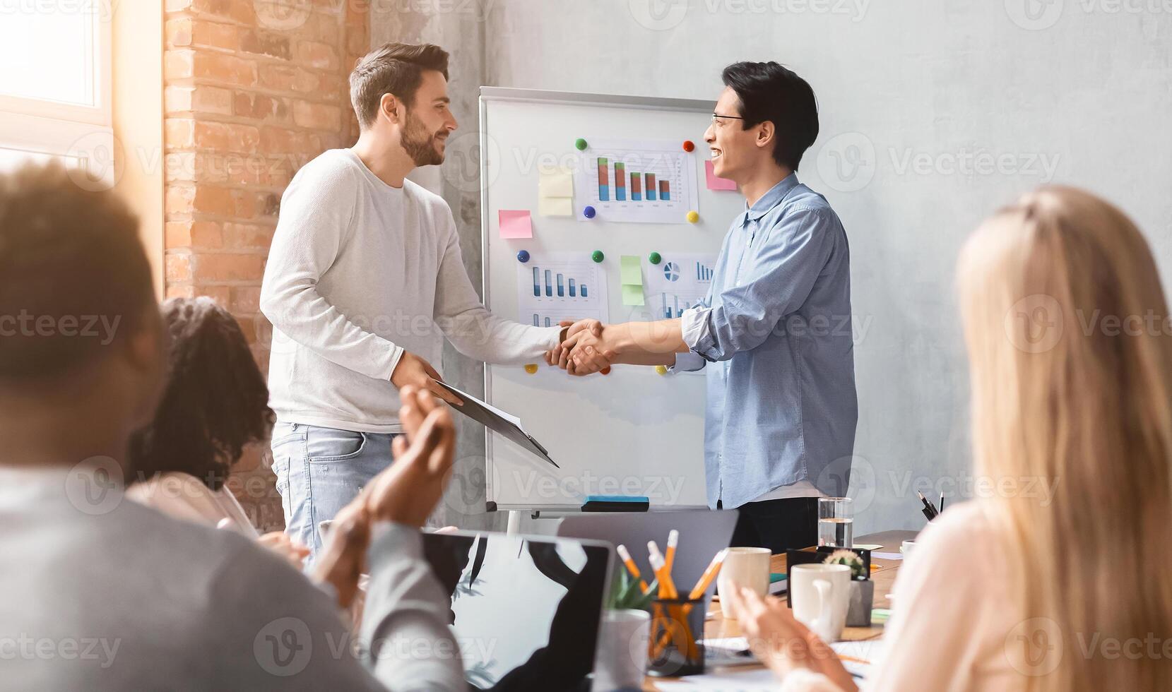 Young guys colleagues shaking each other hands during presentation, international colleagues apllausing, office interior photo