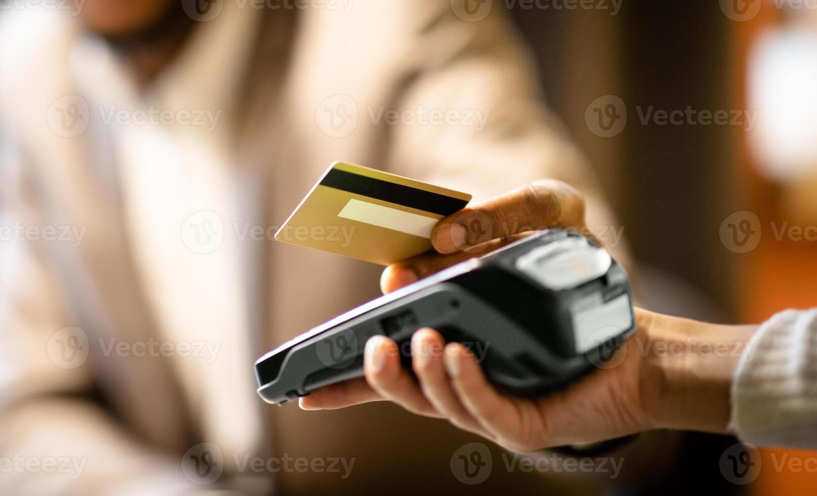 Unrecognizable afro businessman in suit giving credit card to barman paying with gold credit card in cafe, close up photo