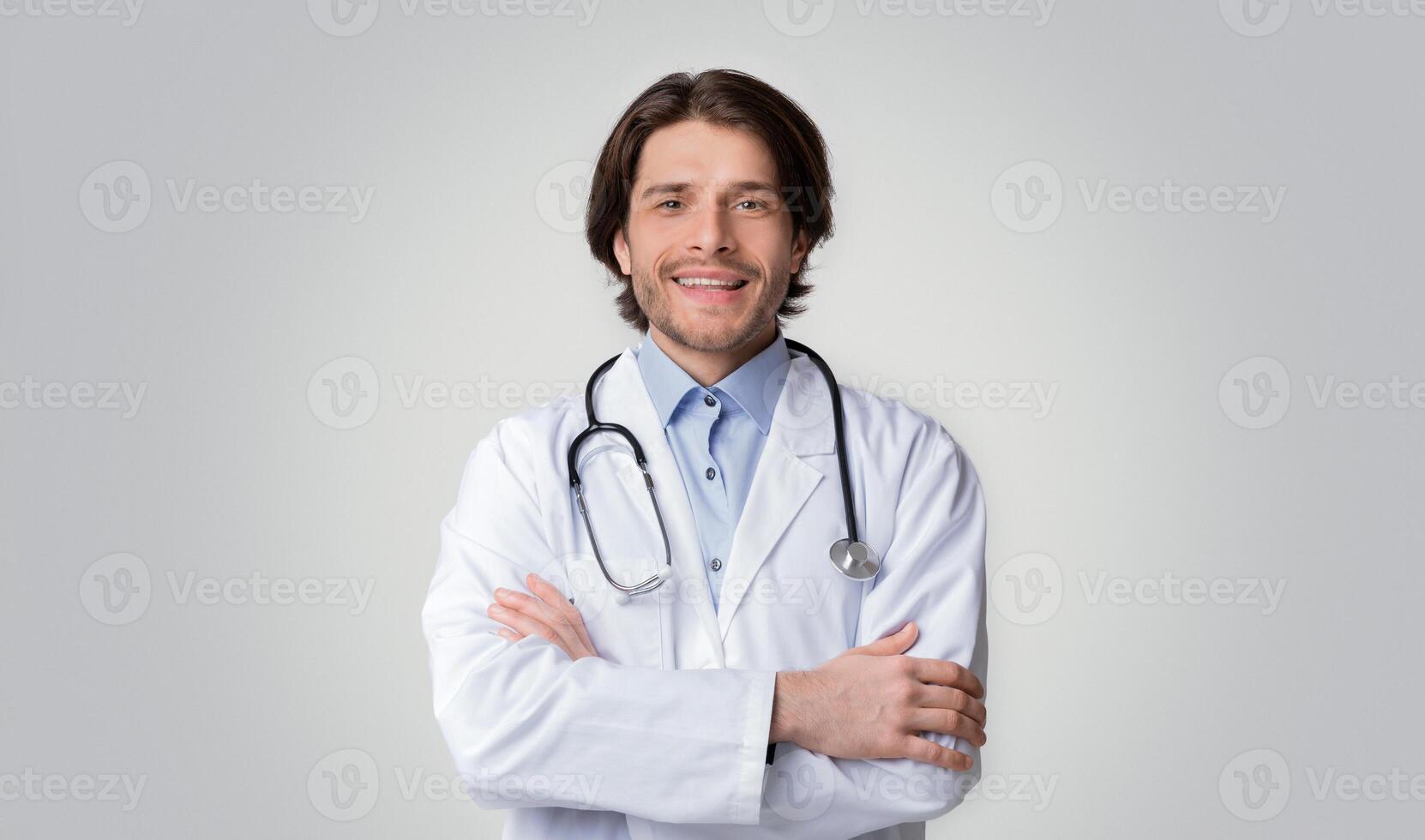 Studio Portrait Of Smiling Medical Specialist Posing With Folded Arms Over White Background, Free Space photo