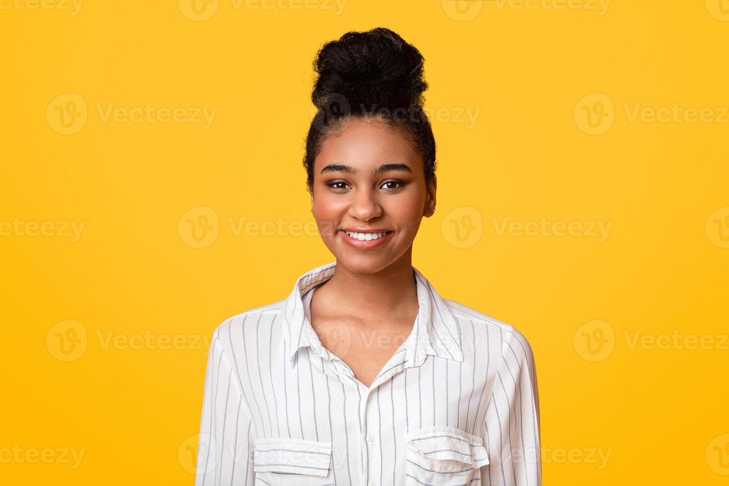 Millennial Afro. Portrait of smiling young african american woman looking at camera and posing over yellow background in studio, empty space photo