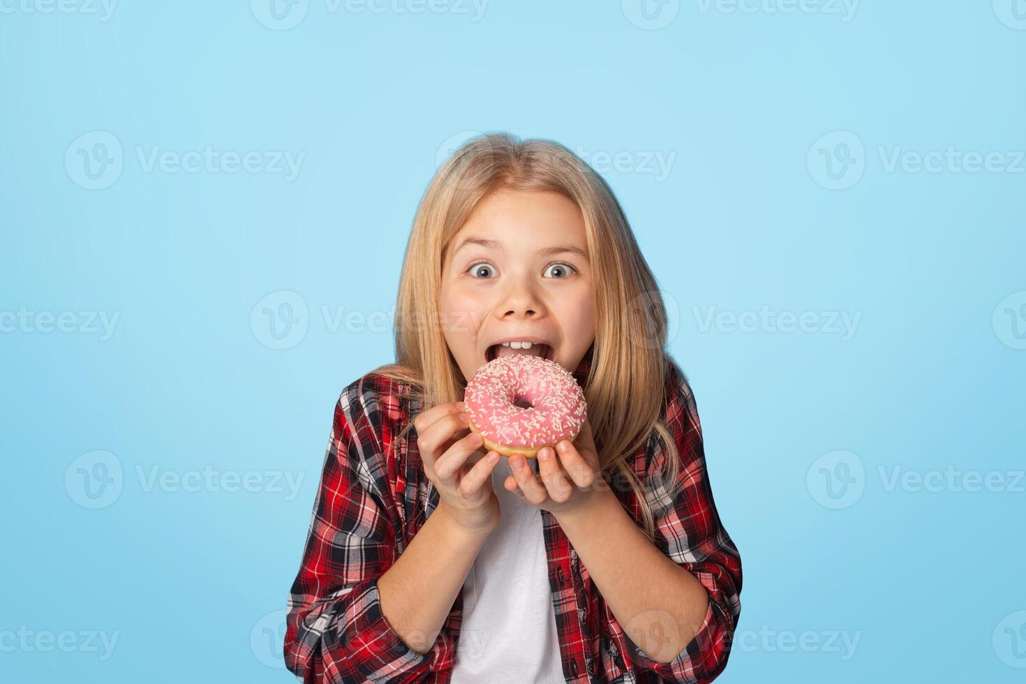 Unhealthy Sweets. Portrait Of Brother And Sister Eating Sugary Donuts And Looking At Camera, Posing Over Blue Background With Free Space photo