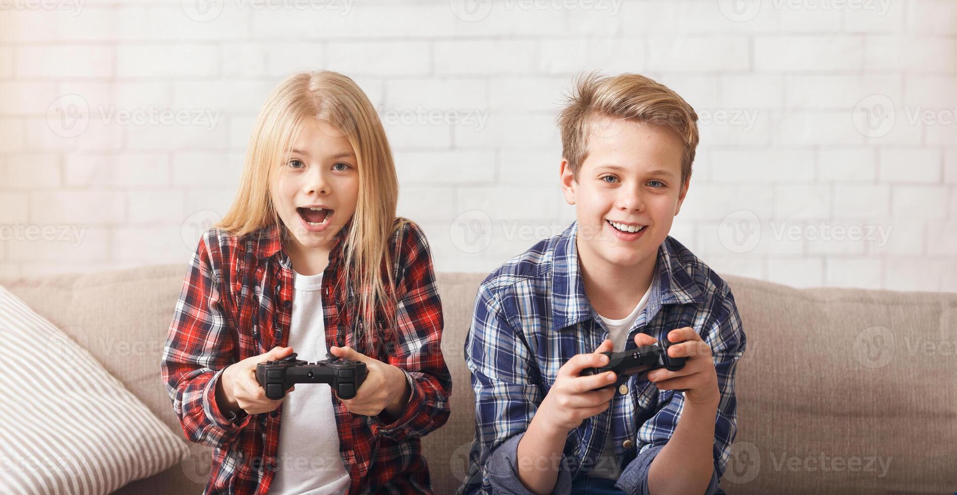 Cute Brother And Sister Playing Game Console Holding Joysticks Sitting On Couch At Home. Children Weekend Leisure. photo