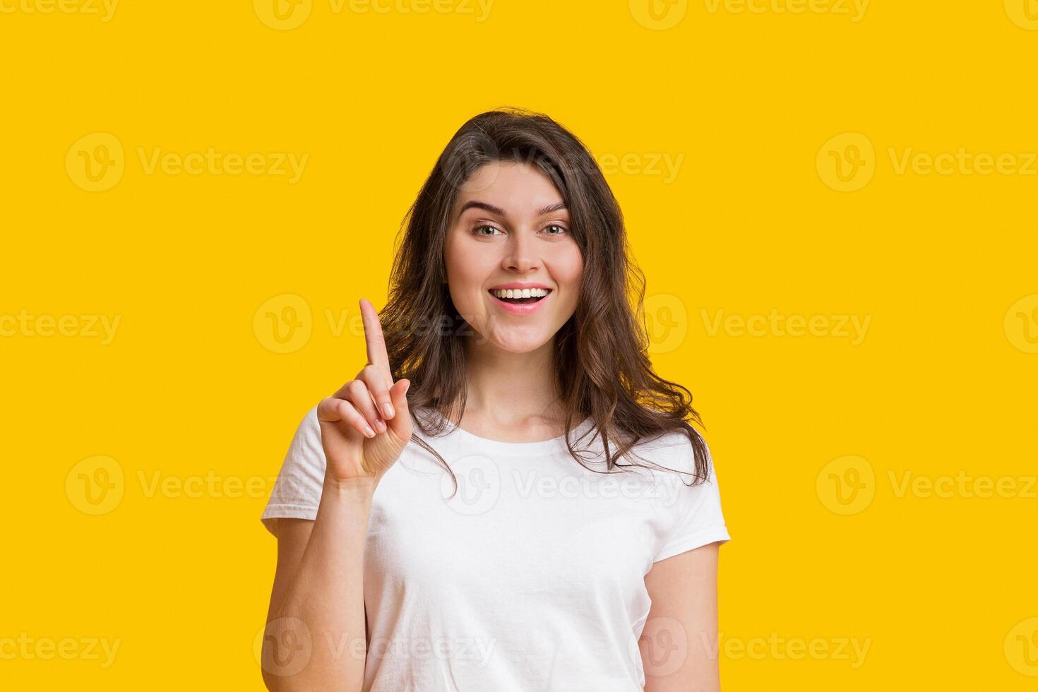 Young Woman Having Idea, Pointing Finger Up, Found Problem Solution, Posing Over Yellow Studio Background With Free Space photo