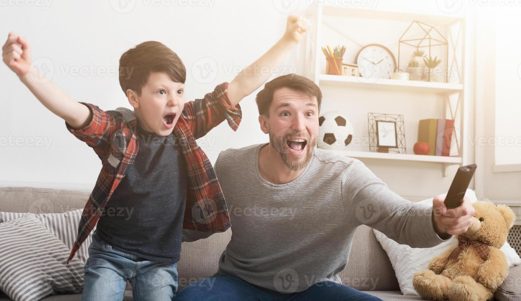 Emotional father and son watching football on TV and cheering favorite team at home photo