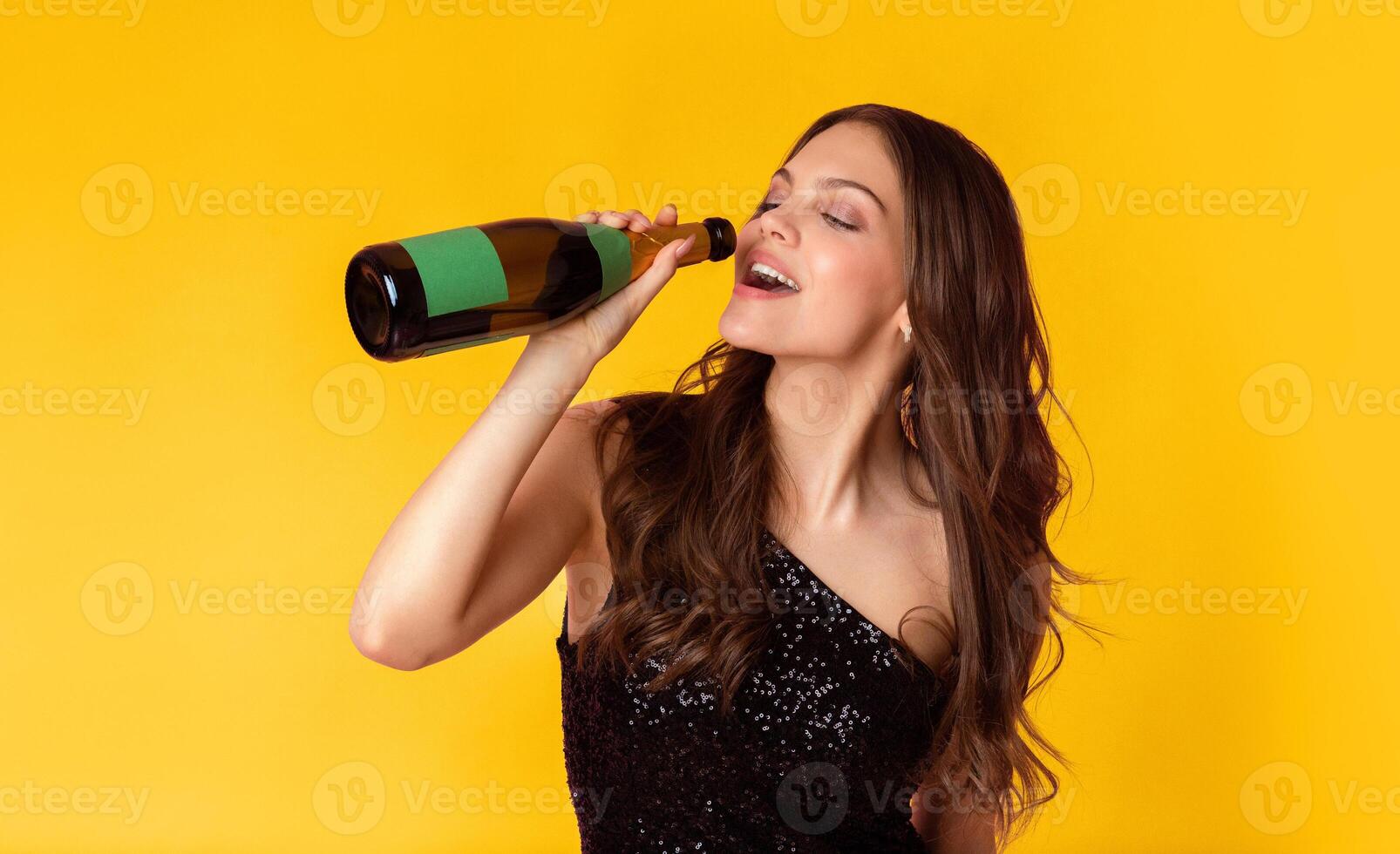 Party Hard Concept. Portrait of young woman in sequin dress drinking from the bottle of champagne, standing over colorful background in studio, free space photo