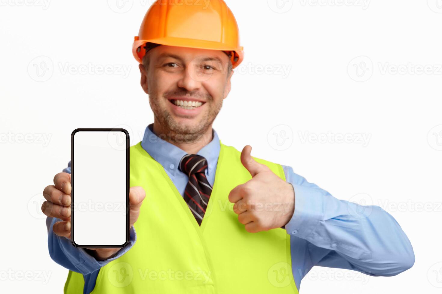 Construction Worker Showing Smartphone Empty Screen Gesturing Thumbs-Up, Recommending Architectural And Building Services On White Background. Selective Focus photo