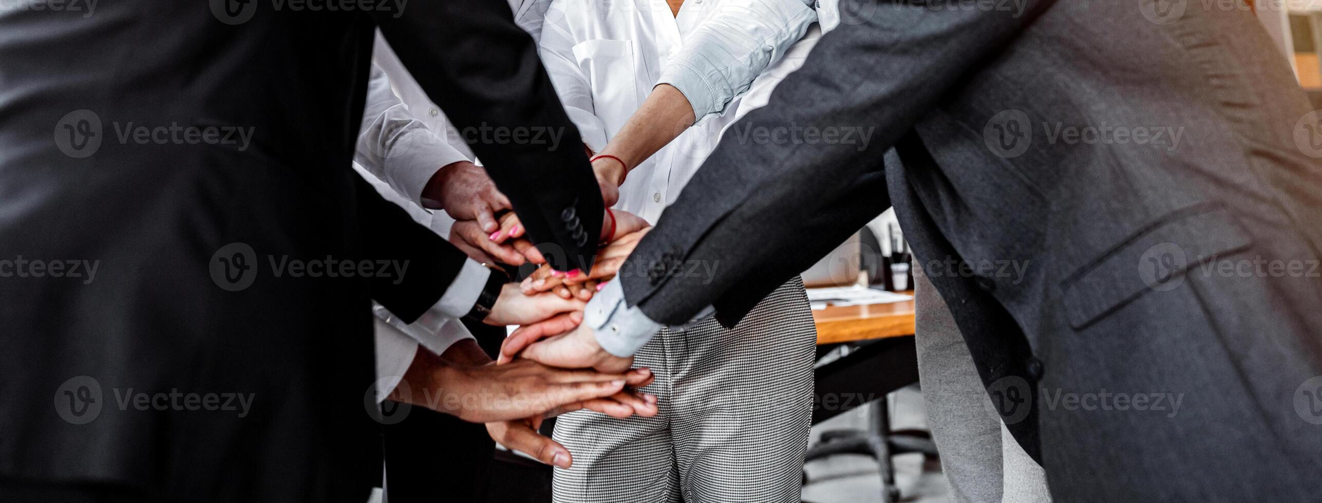 Teambuilding And Corporate Spirit. Joyful Colleagues Holding Hands Standing In Circle During Meeting In Modern Office. Selective Focus photo