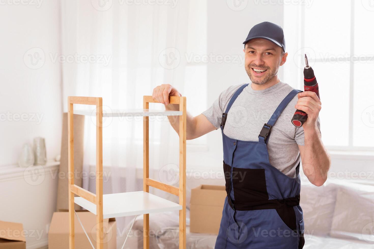Furniture Assembly. Handyman Worker Posing Installing Cabinet Holding Electric Drill Standing Posing Indoors. Free Space photo