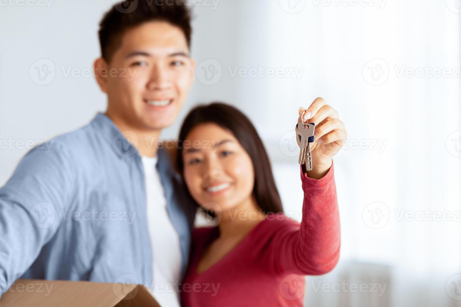 Happy korean family showing keys from their new apartment to camera, selective focus, empty space photo