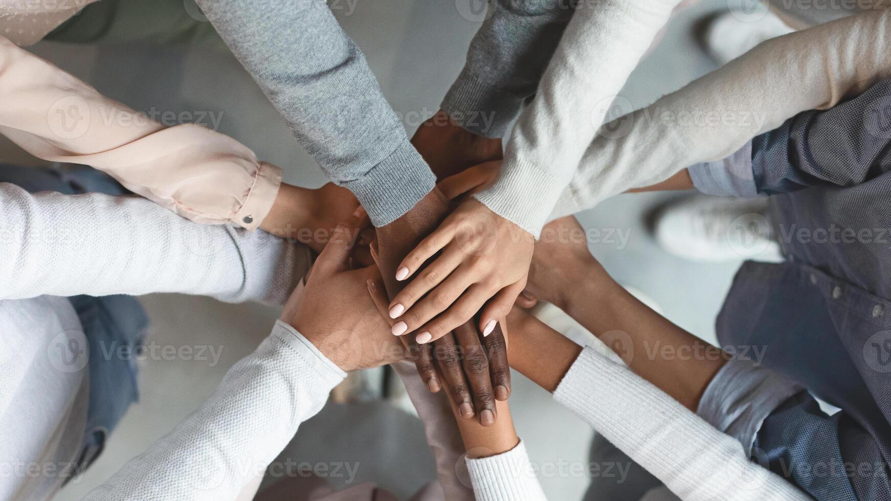 Close up of international business team showing unity with putting their hands together on top of each other. Concept of teamwork, top view photo