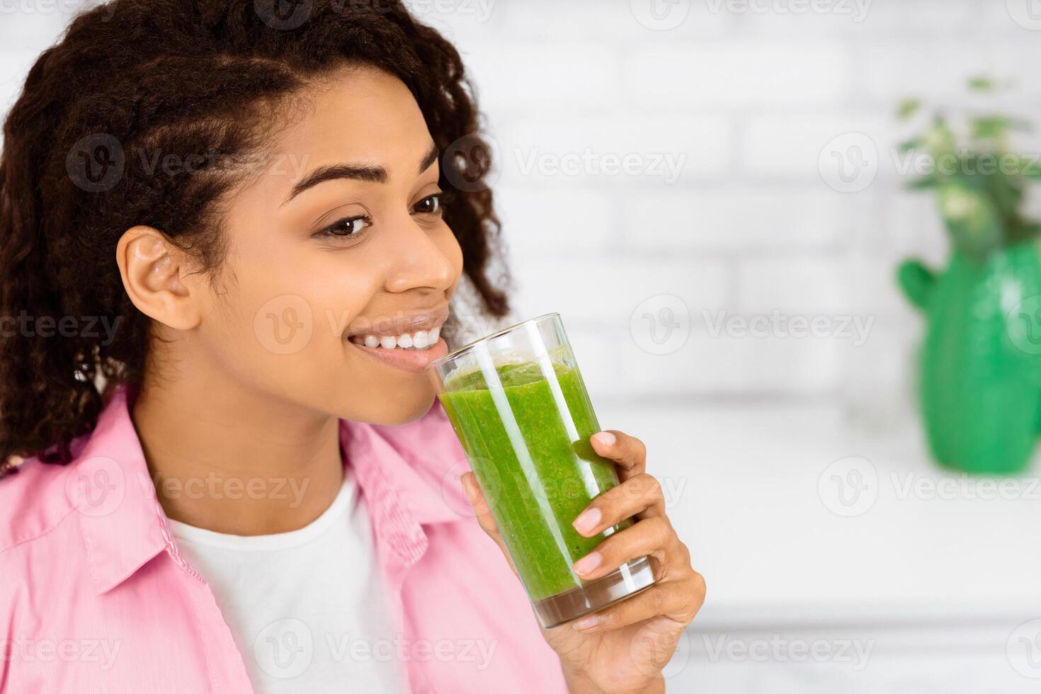 Healthy Lifestyle Concept. Close up portrait of smiling black girl drinking morning smoothie made of super foods photo