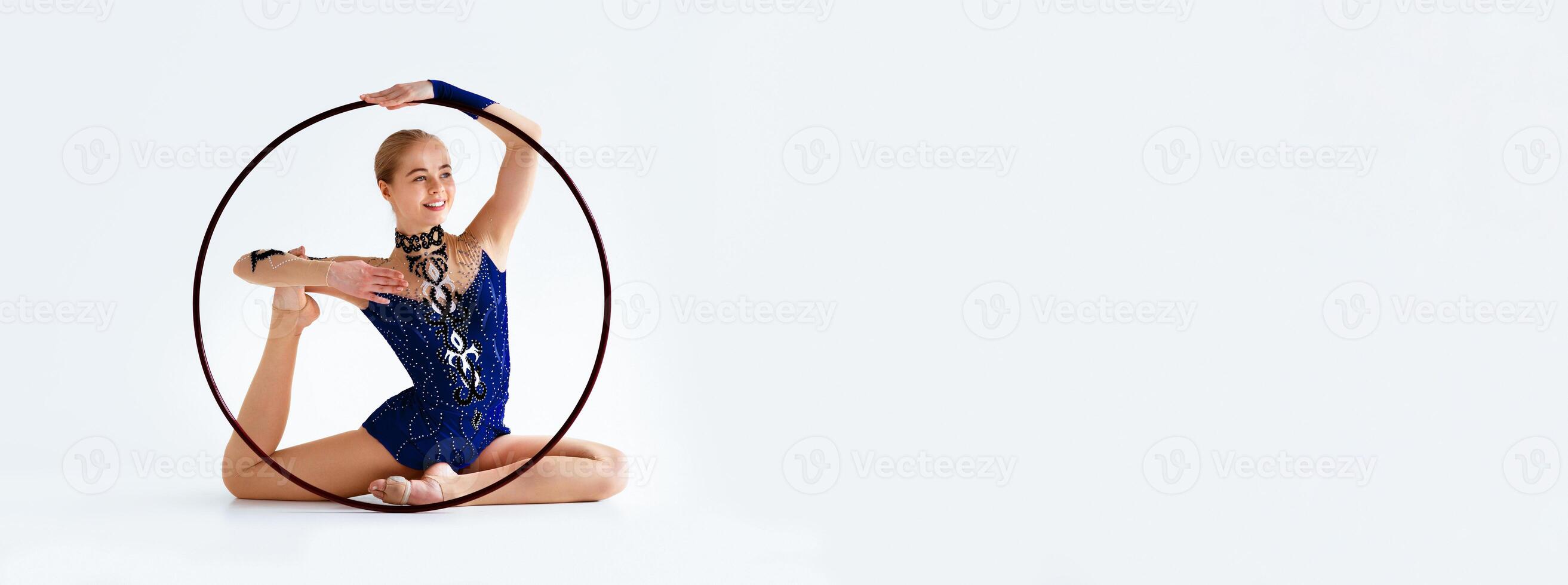 Female athlete doing complicated gymnastic exercise with hoop on white background, panorama with copy space photo