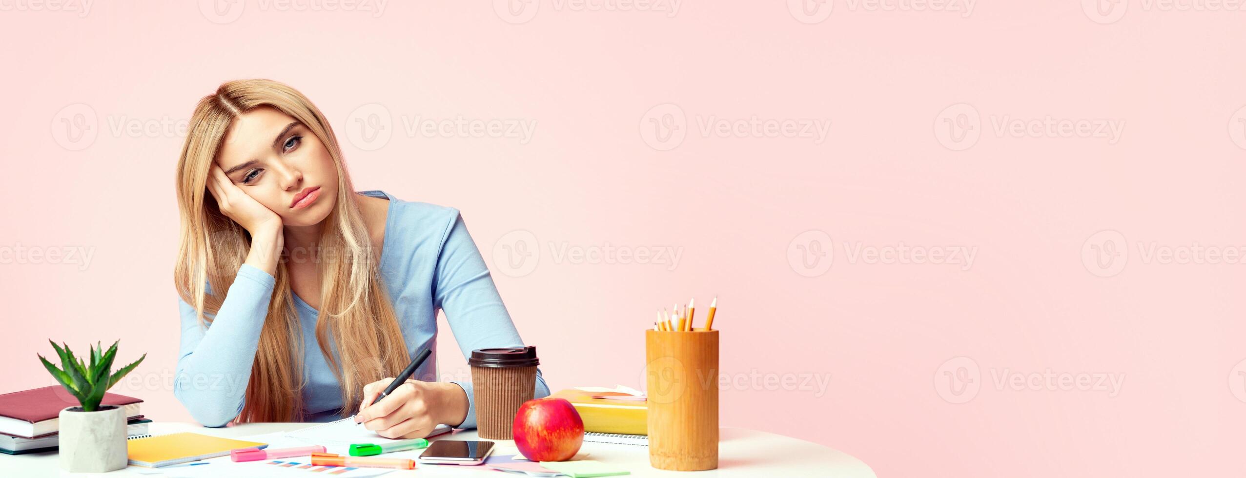 Exhausted Student, Education And Overworking Concept. Tired girl preparing for exams, falling asleep, writing in notebook photo