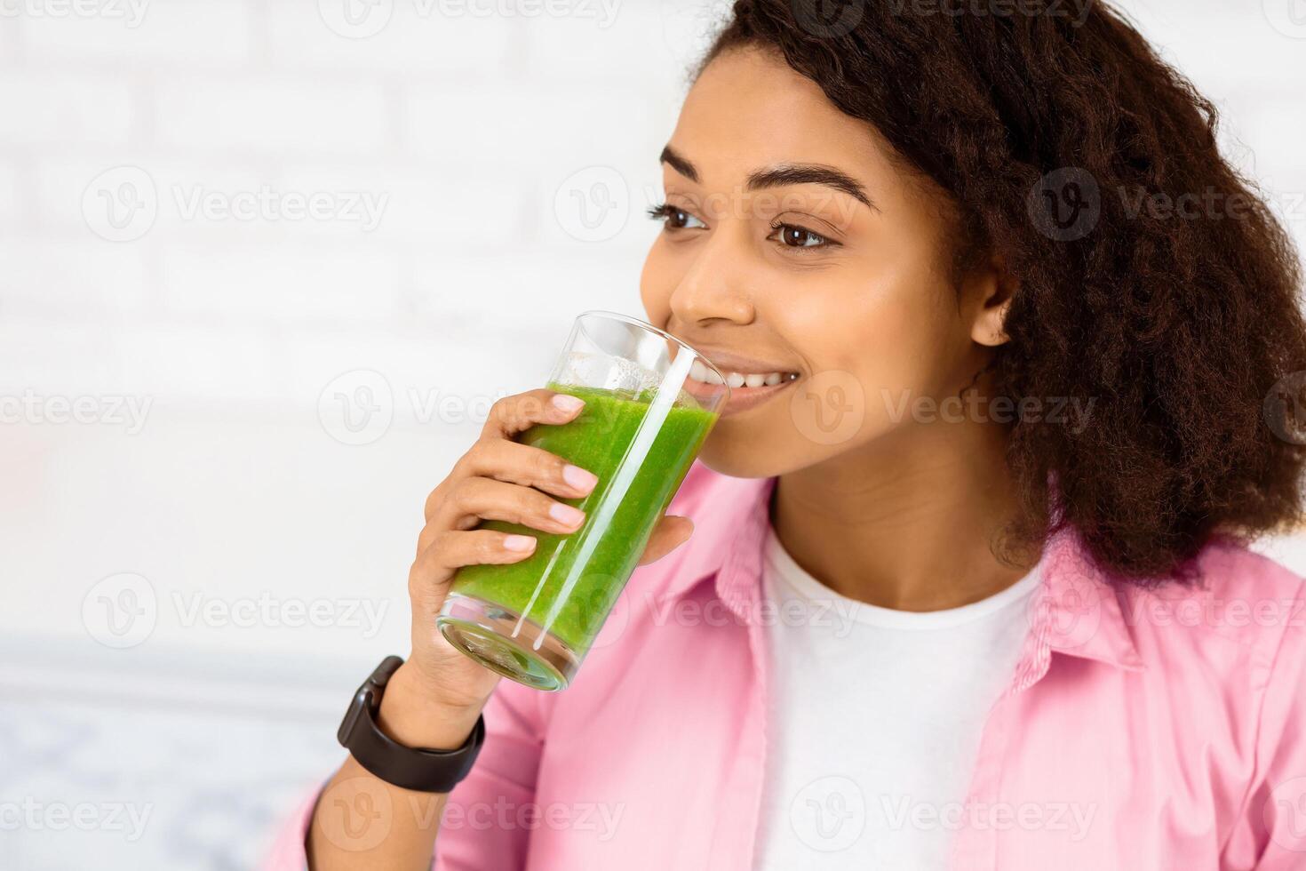 Boost Your Immune System. Headshot of afro woman drinking homemade green juice, looking aside at copy space photo