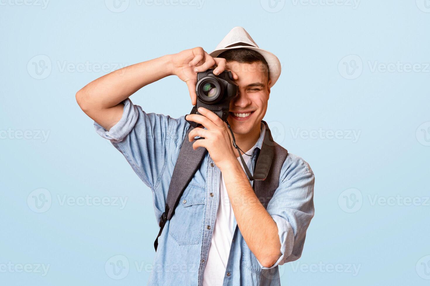 Excited traveler young guy taking photos, using camera over orange background photo