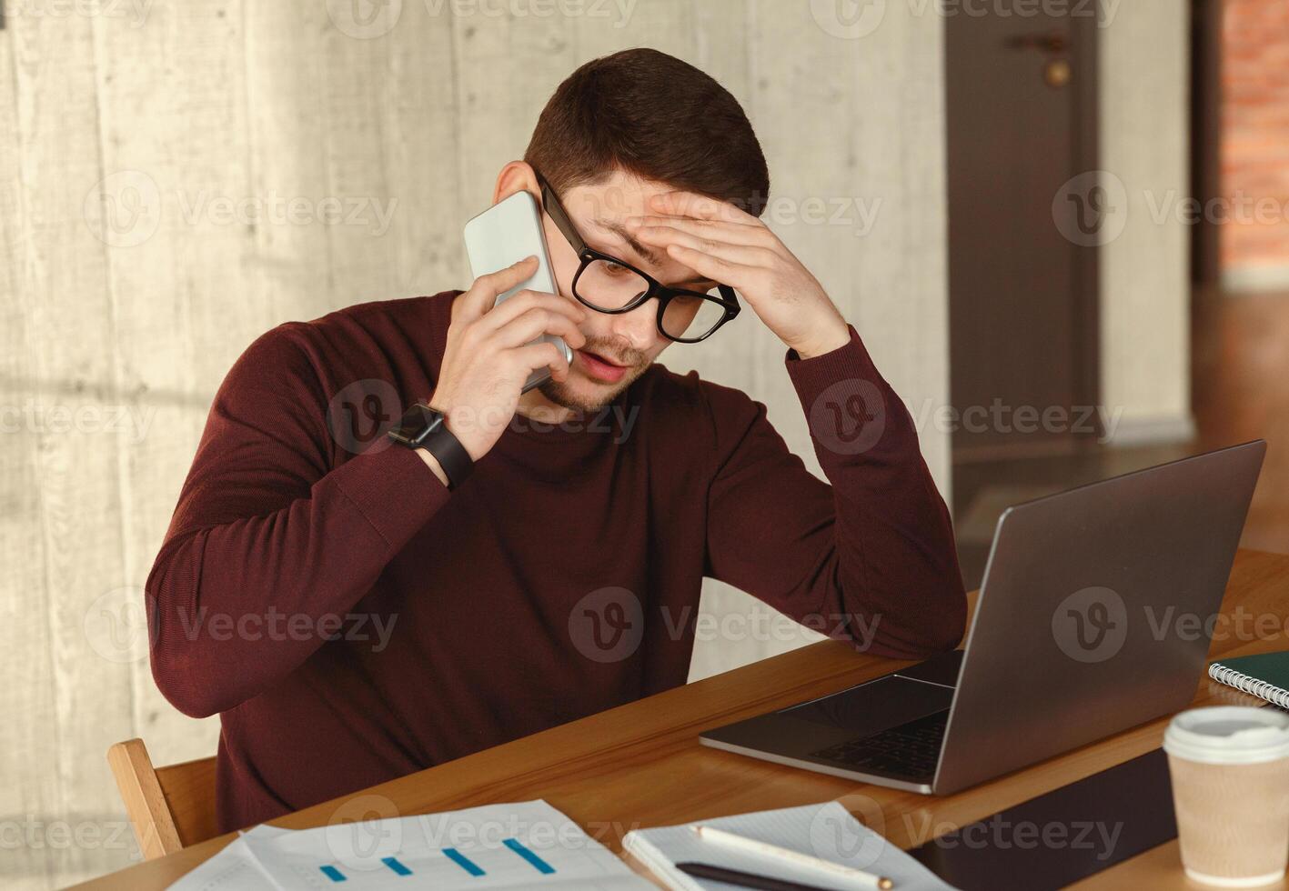 Tired Manager Guy Talking On Cellphone Working Sitting At Laptop In Modern Office. Selective Focus photo