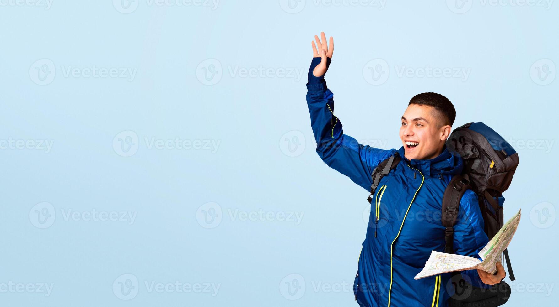 Emotional backpacker with map found a place, gesturing over orange background, looking at copy space photo