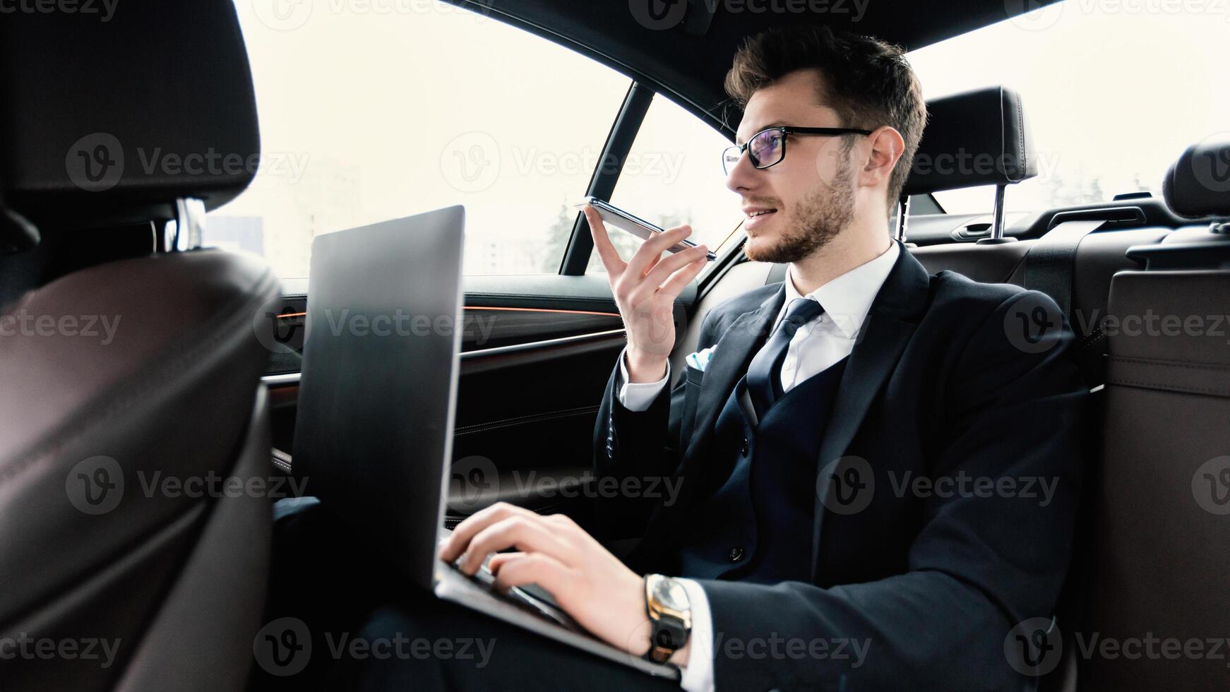 Voice Recognition, Search Technology Concept. Worker in glasses using smart phone and pc sitting in car photo