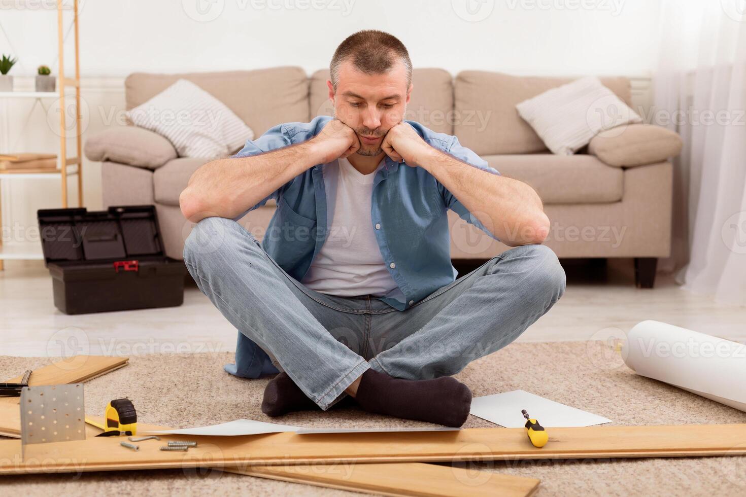Furniture Assembly Trouble. Sad Man Sitting Near Disassembled Shelf Having Problems Installing Self-Assembly Kit At Home. photo