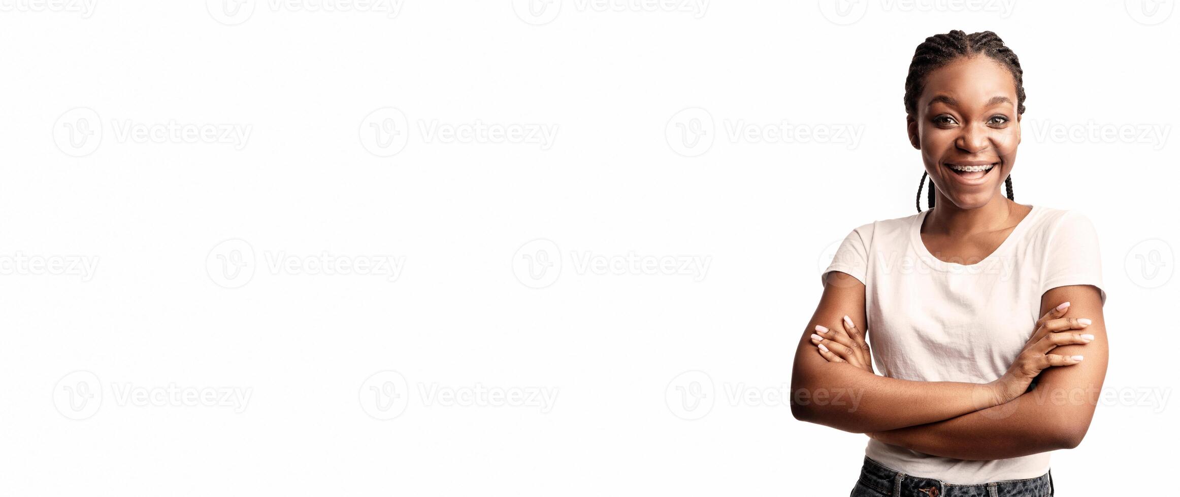 Positive African Lady With Braces Posing Crossing Hands Smiling To Camera Over White Studio Background. photo