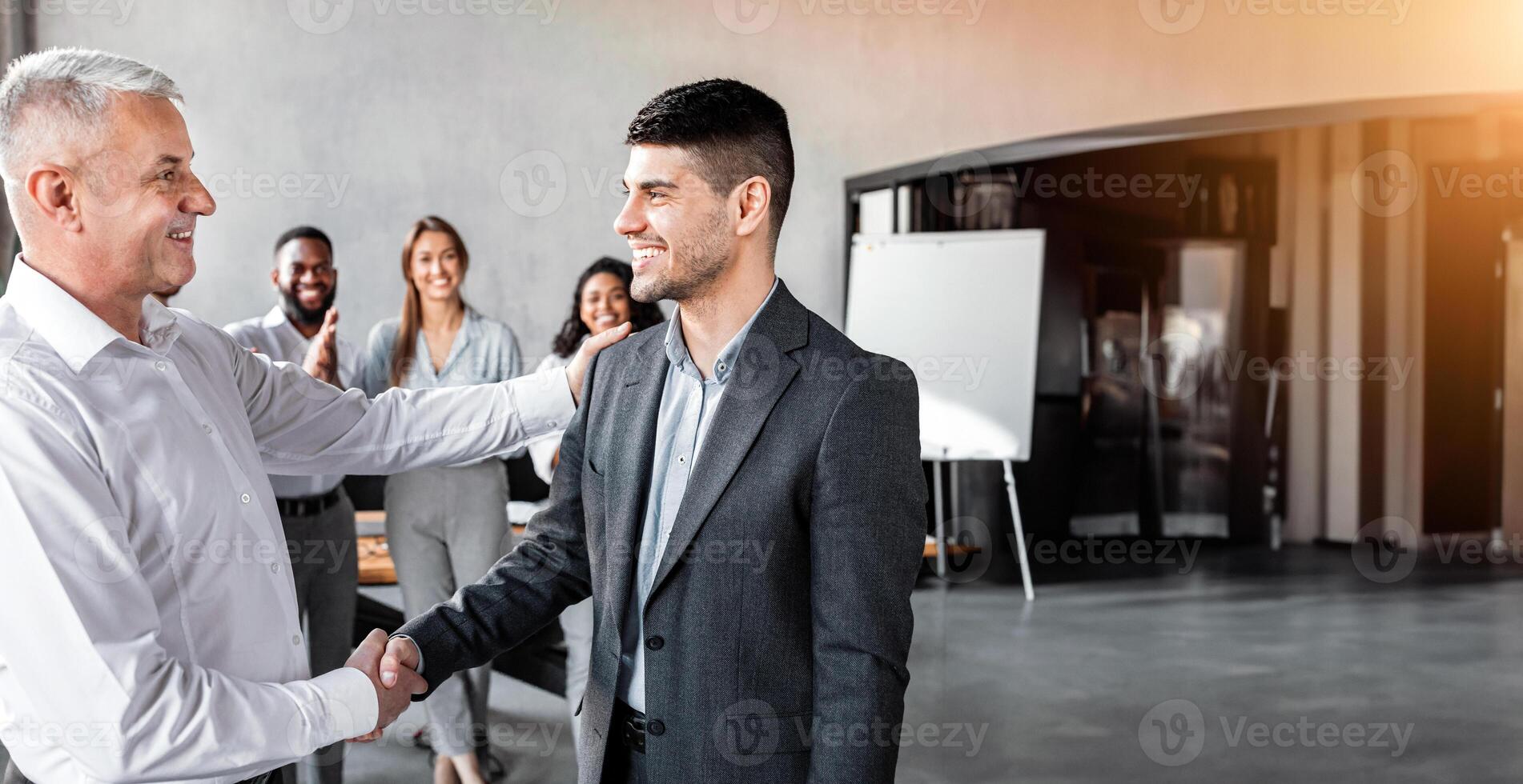 Career Promotion. Businessman Shaking Hands With Employee During Corporate Meeting Standing In Modern Office. Selective Focus photo