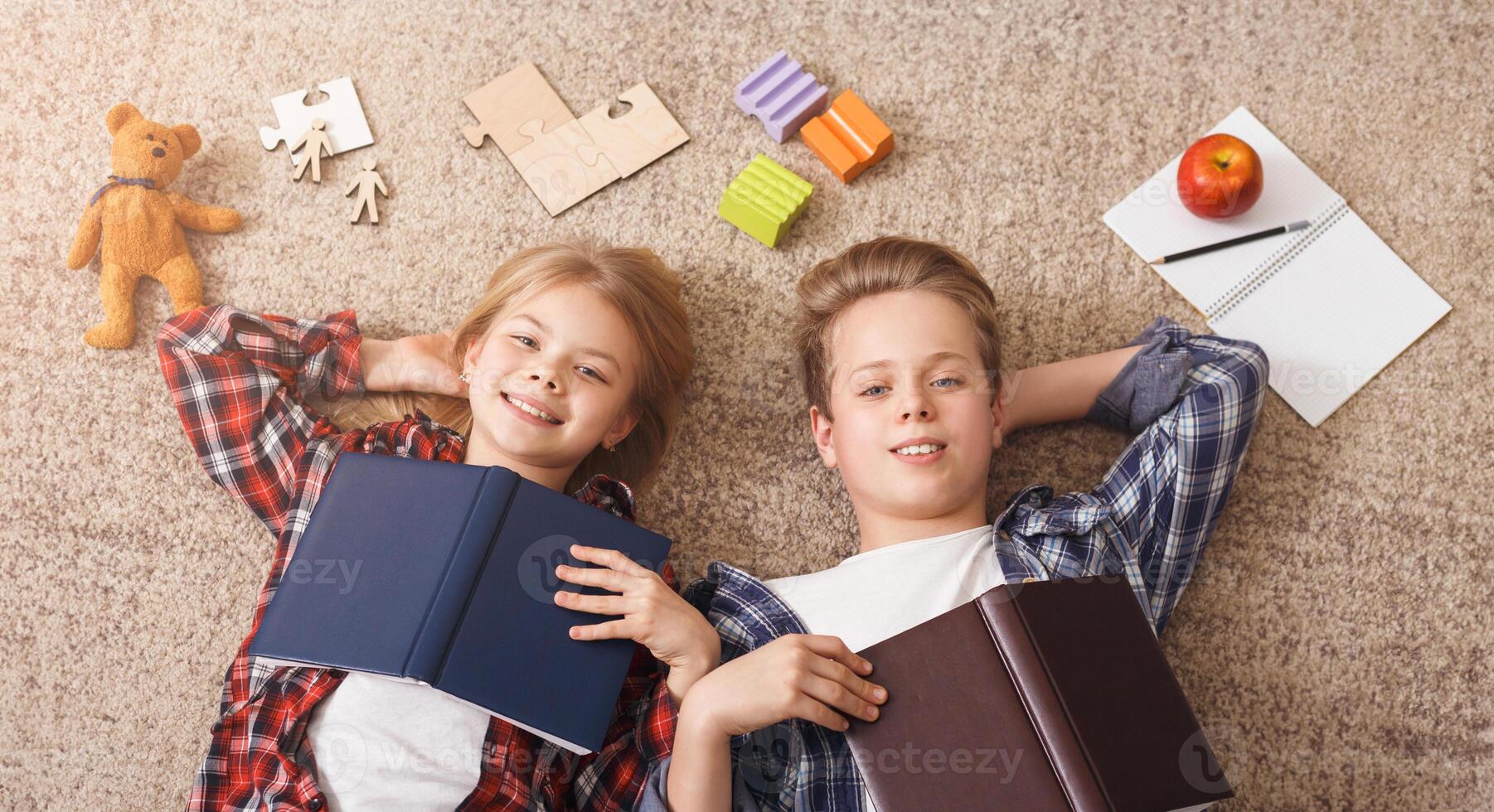 Siblings Brother And Sister Doing Homework Together Lying On Floor Having Fun Posing With Books At Home. Top View photo