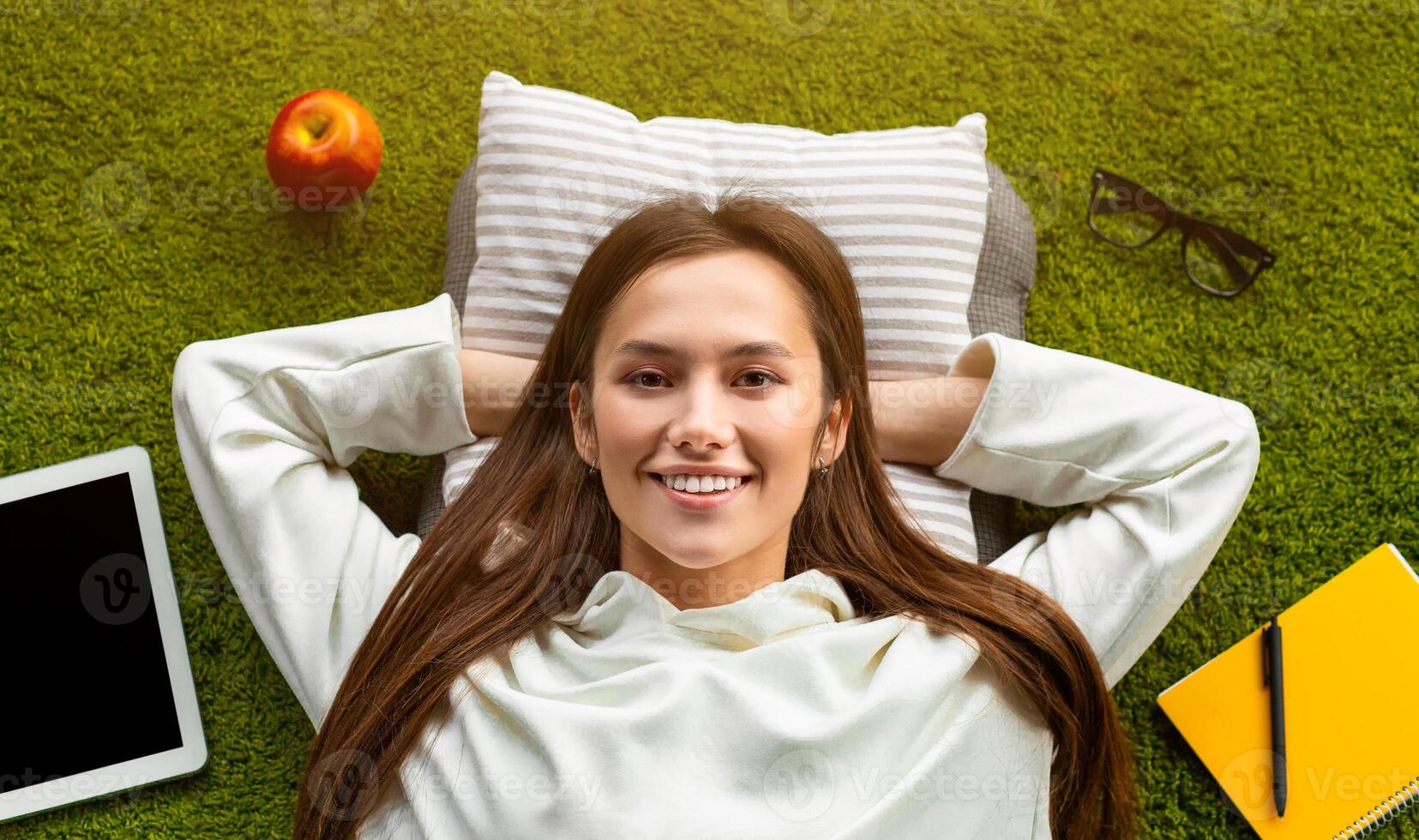 Smiles girl with glasses and Appllies on the floor hands behind head. Top view, work at home concept photo