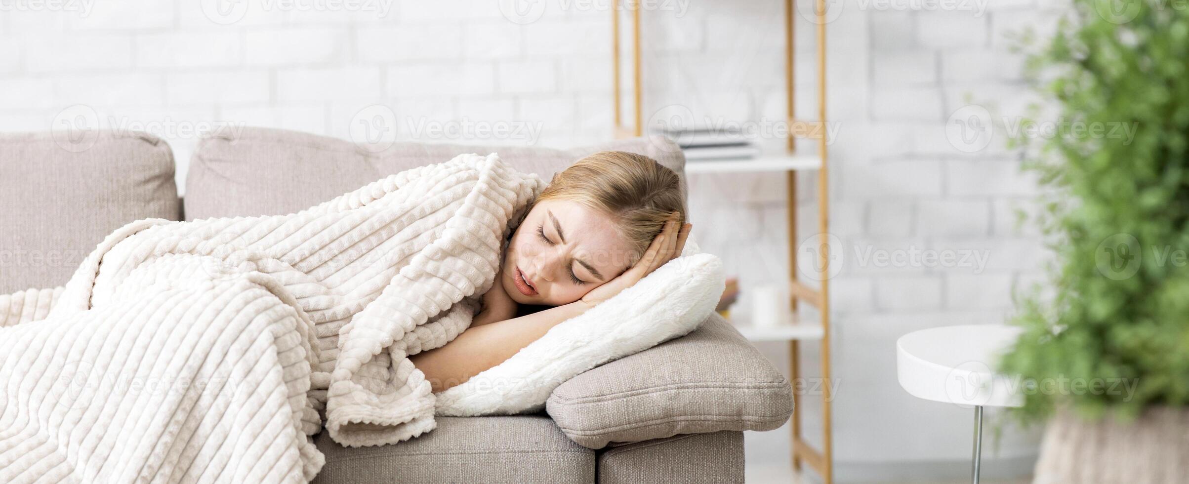 Cold and flu. Afflicted girl laying on couch wrapped in blanket, feeling sick, panorama with copy space photo