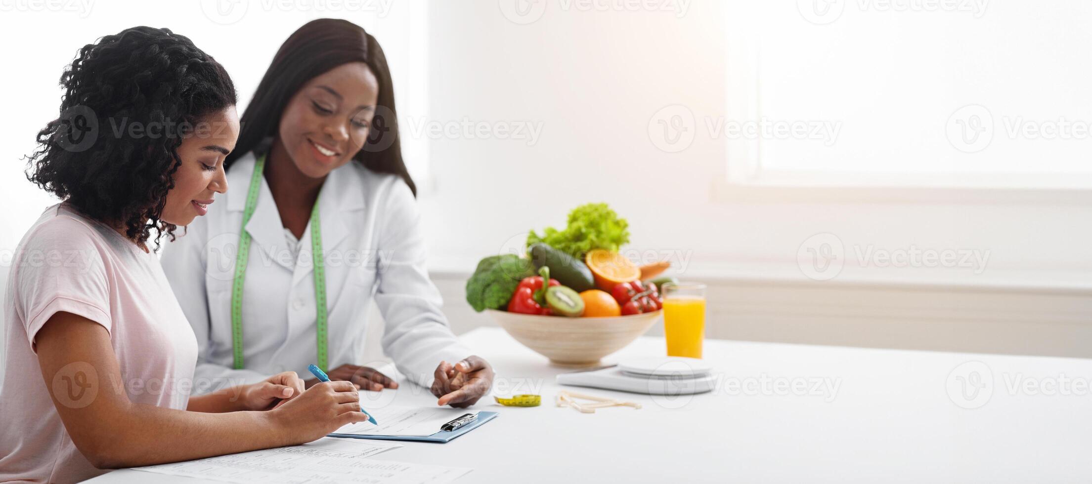 African american women dietologist and patient discussing new diet at clinic, empty space photo