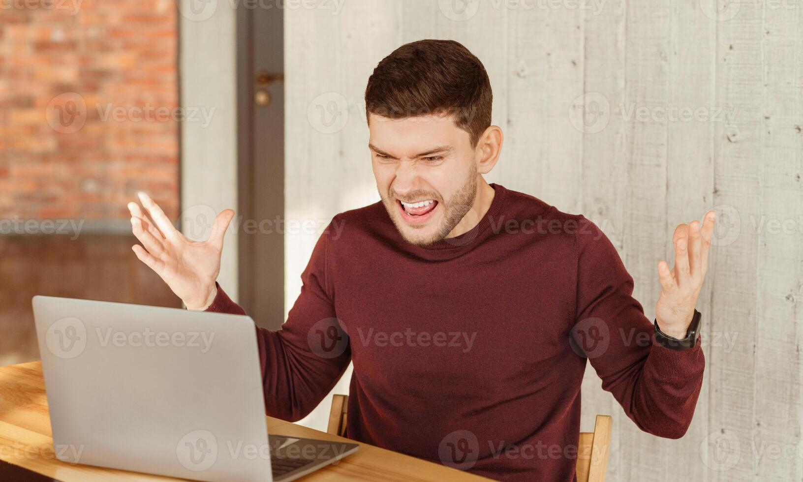 Angry Office Worker Shouting Sitting At Laptop Gesturing Having Problem With Computer At Workplace Indoor. Selective Focus photo