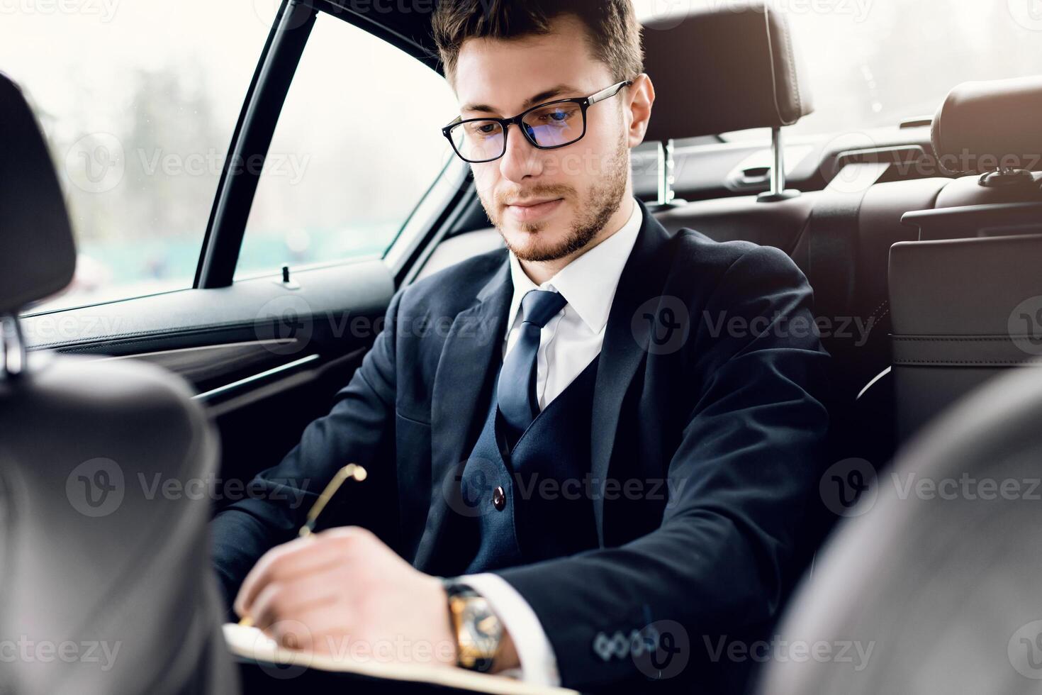 Transportation And Ownership Concept. Young handsome man reading and signing documents inside his new car photo