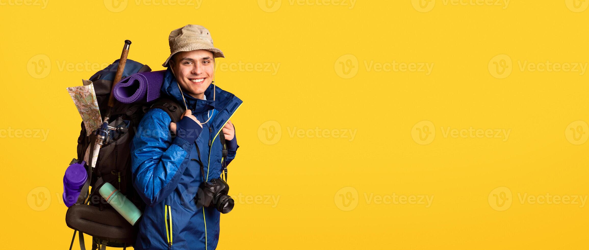 Banner for tourist equipment shop. Excited hicker with big backpack over yellow studio background, panorama with copy space photo