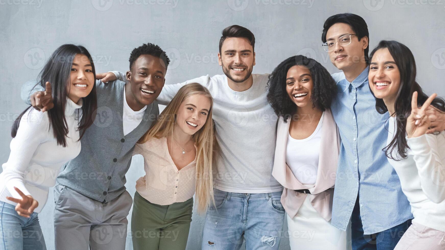 Portrait of happy young international business team posing over grey background, panorama photo