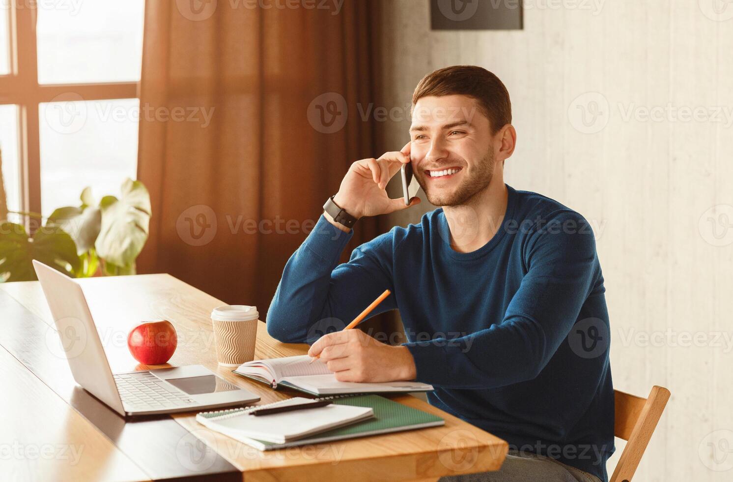 Successful Entrepreneur. Young Businessman Talking On Cellphone Sitting At Laptop Working In Modern Office. Copy Space photo