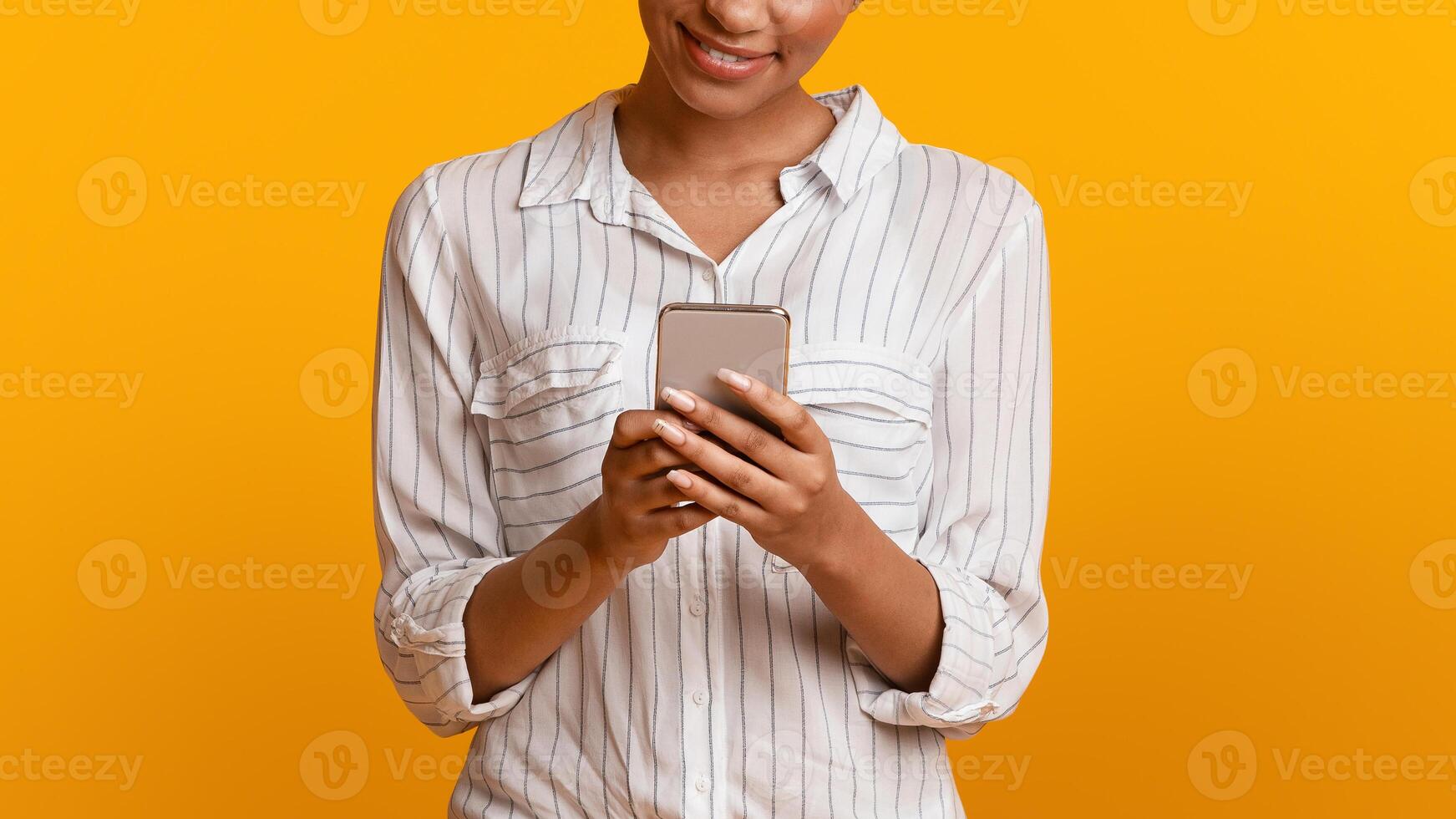 Modern Smartphone In Hands Of Unrecognizable African American Girl Standing On Yellow Background In Studio, Panorama With Empty Space photo
