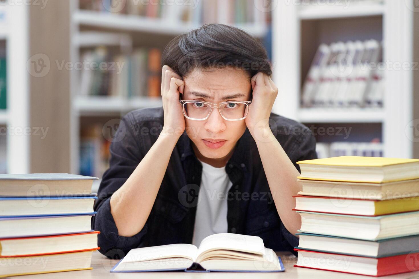Studying Too Much. Tired asian student in specs grabbing his head, preparing for exams, trying to focus, copyspace photo