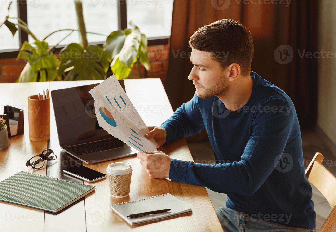 Business Career. Young Manager Guy Looking At Graphs And Charts Working Sitting In Modern Office. Selective Focus photo