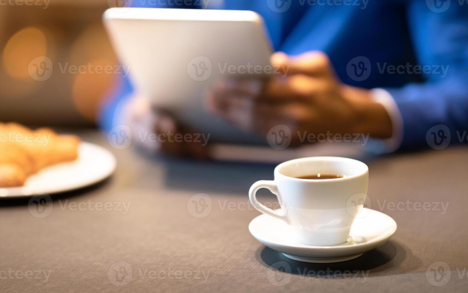 Coffee Break. Unrecognizable afro guy using tablet computer at cafe and drinking coffee, focus on cup, copyspace photo