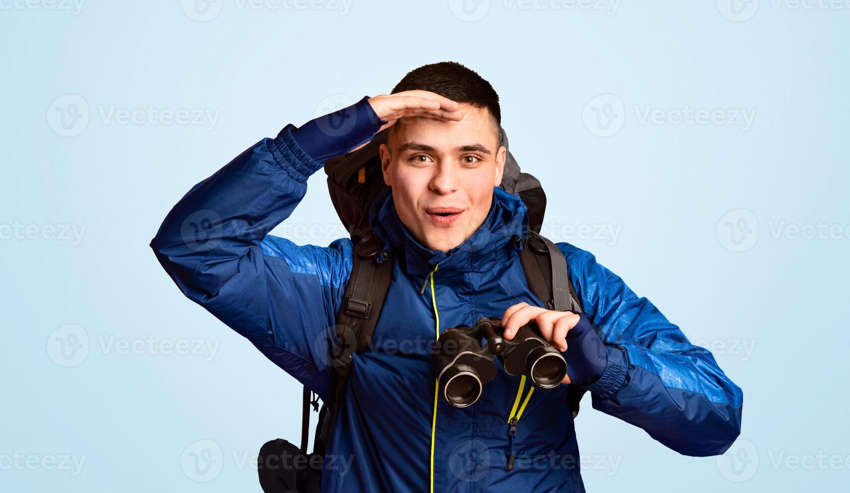 Emotional traveler young guy making sightseeing, using modern binoculars, orange background photo
