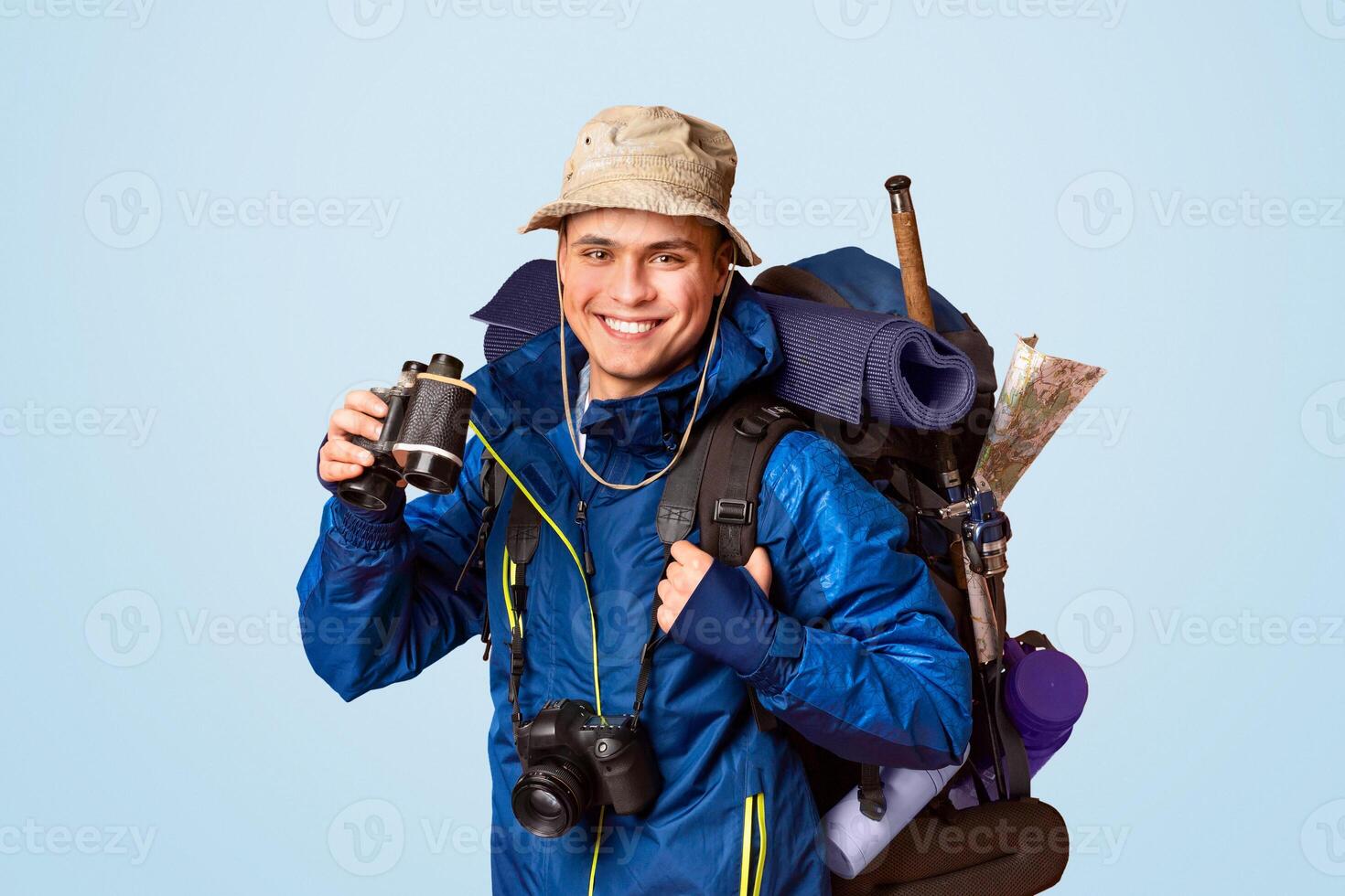 Hiker with binoculars smiling over orange studio background, panorama photo