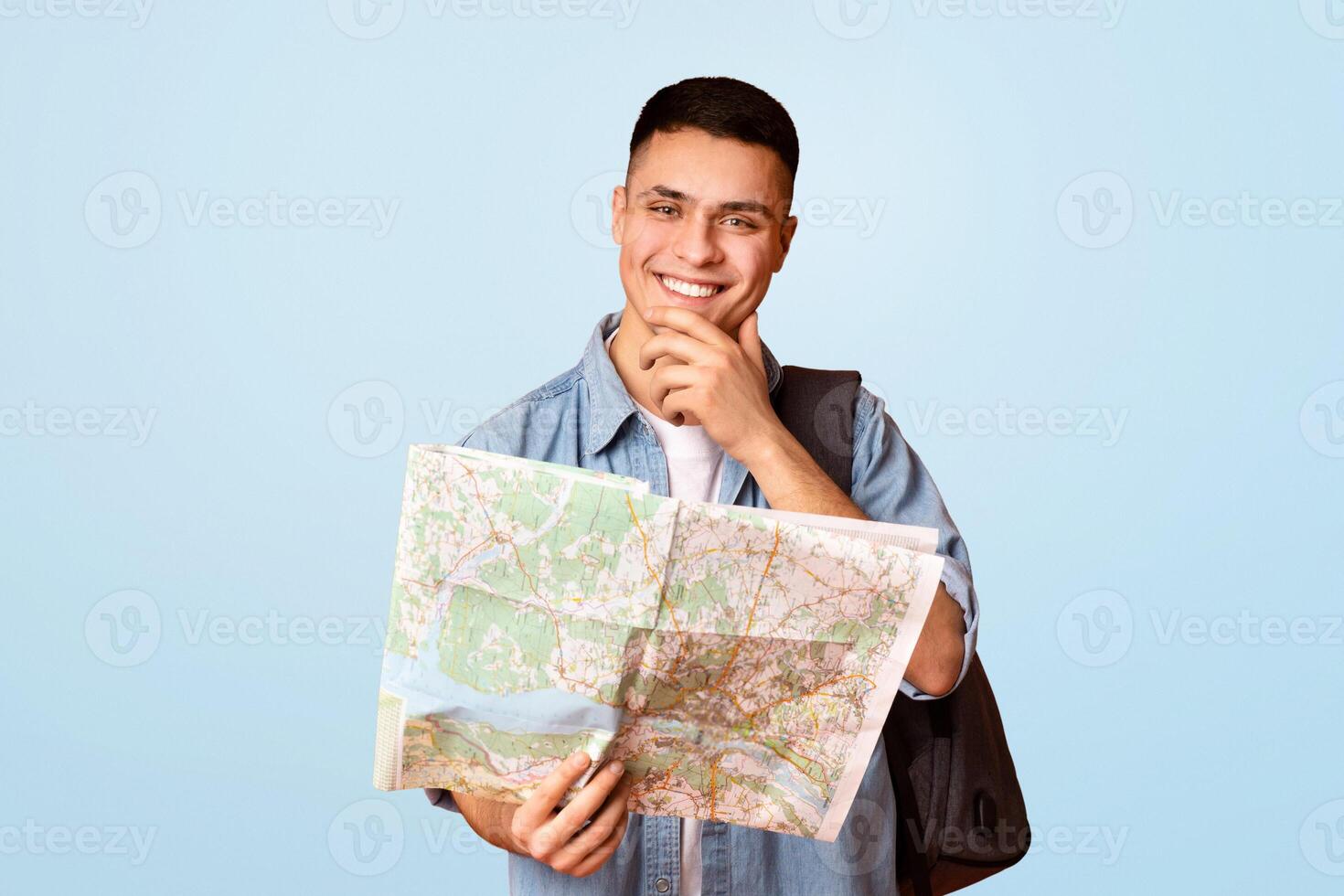 Positive guy making sightseeings, using city map over orange background photo