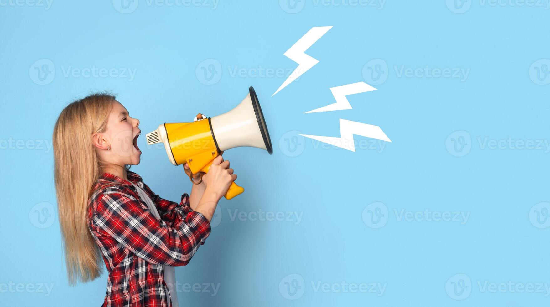 Emotional little girl shouting at copy space with megaphone, making announcement, sharing news on blue studio background, panorama photo
