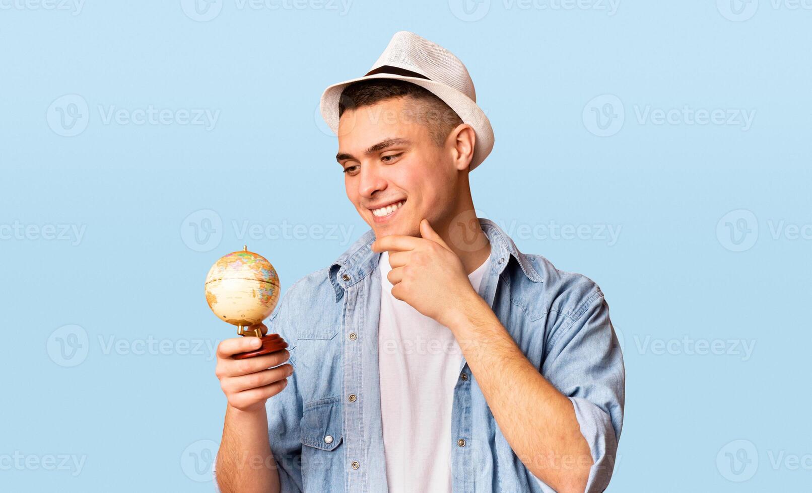 Excited tourist holding small globe, looking where to go next, orange background photo