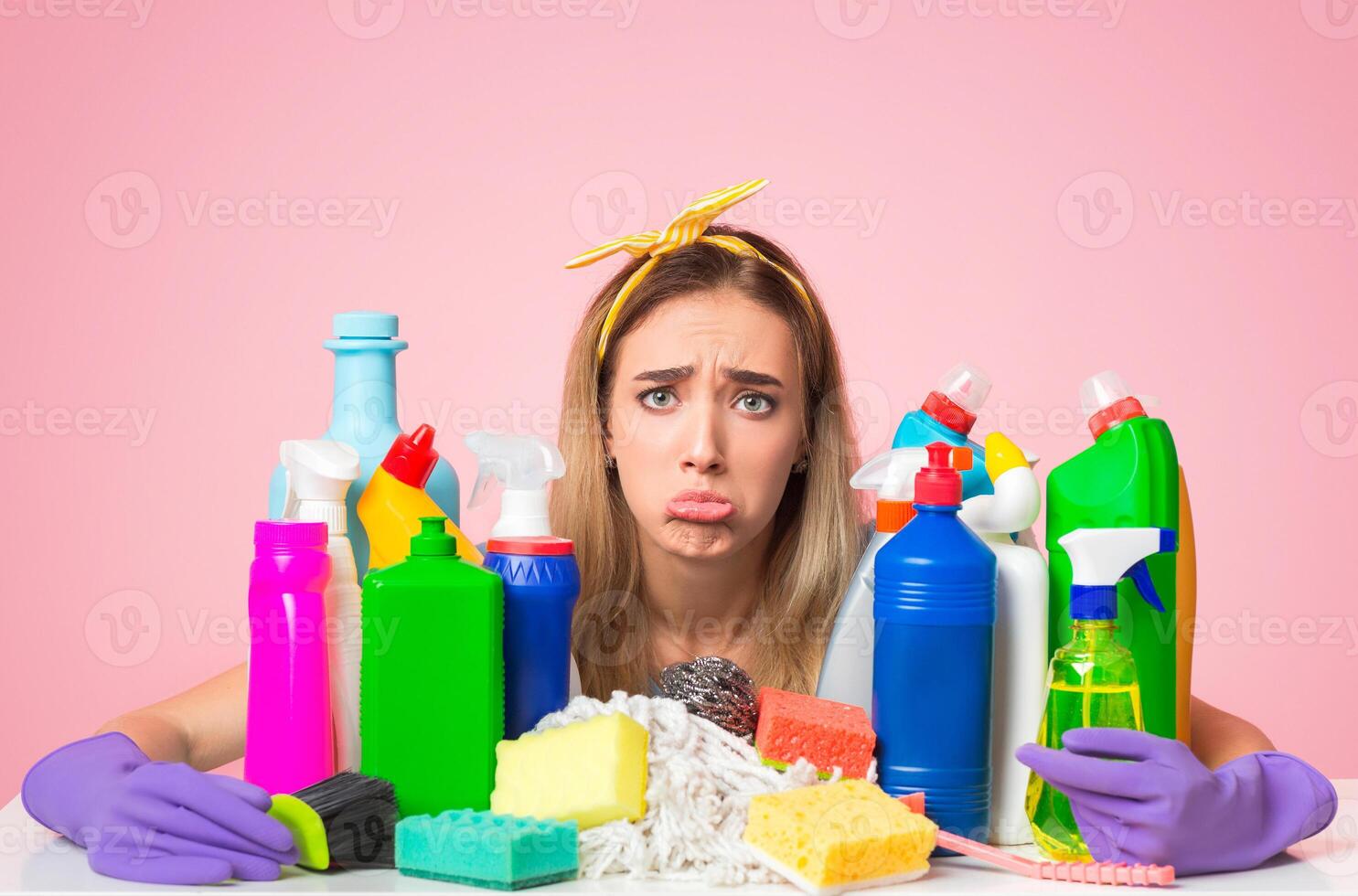 Problems with cleaning at home concept. Sad funny housewife hugs cleaning supplies, studio shot photo