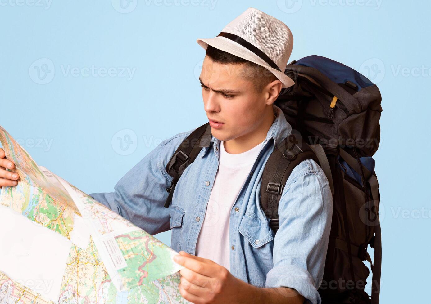 Close up of lost traveler with backpack looking at city map over orange background, empty space photo