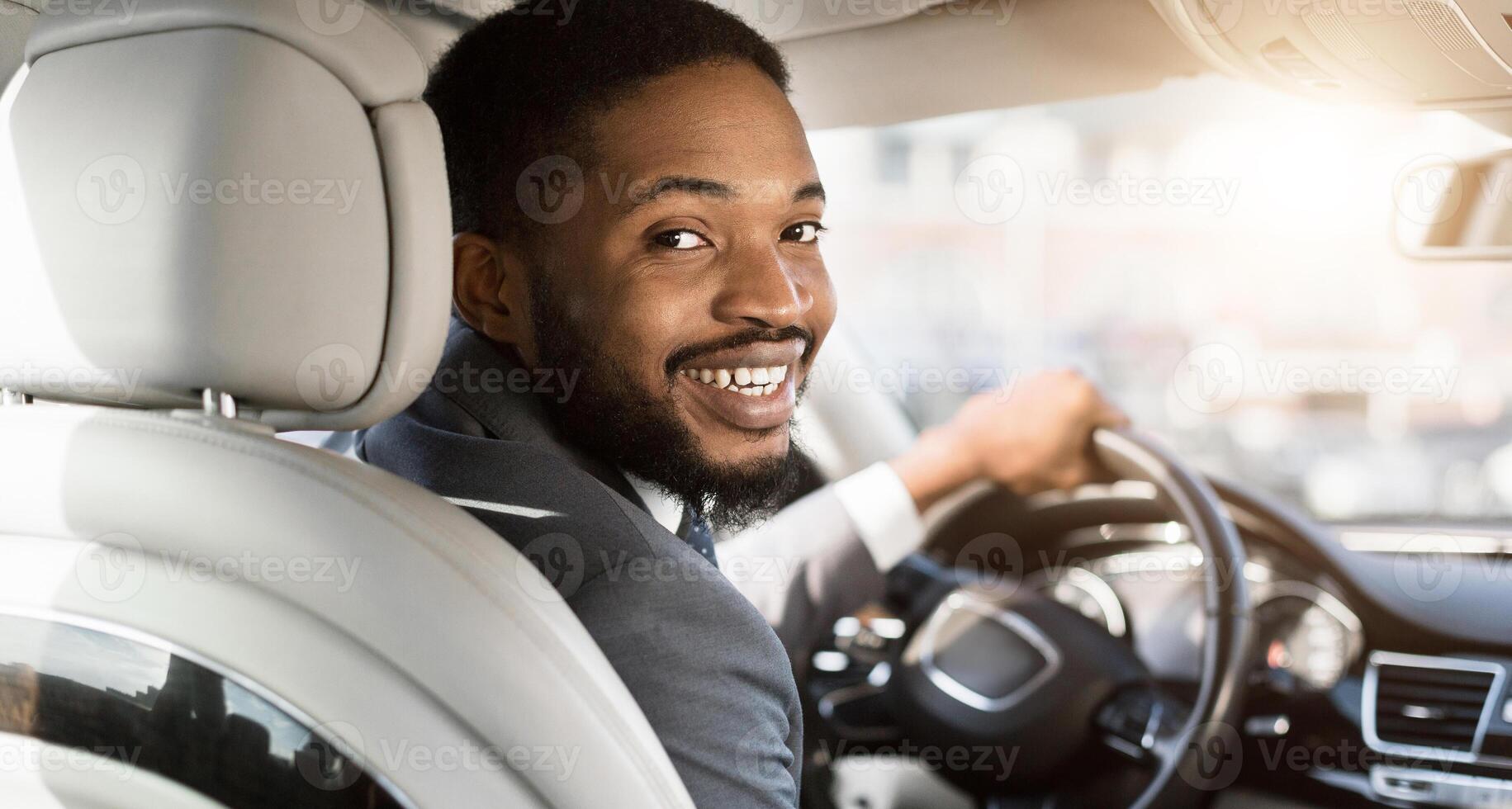 New Car. Cheerful Black Man Driving New Automobile After Purchase Sitting In Driver's Seat In Auto. Panorama, Selective Focus photo