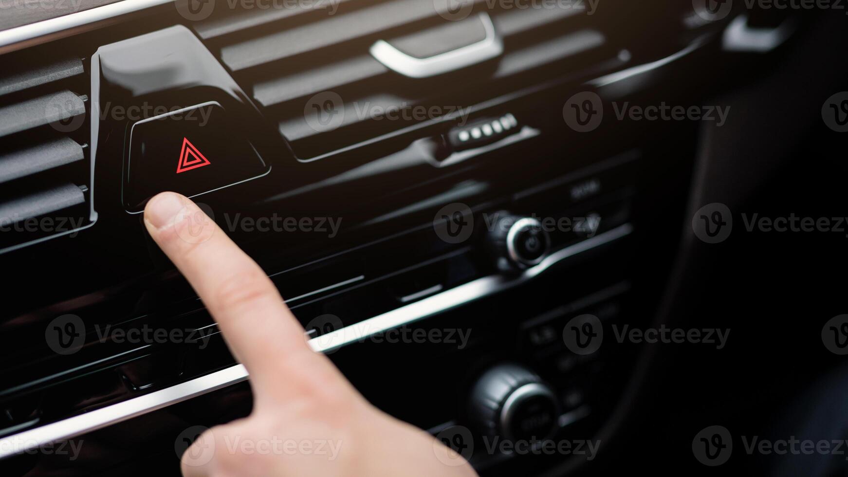 Warning Concept. Man pushing red triangle car hazard lights button in his luxury auto, being towed photo