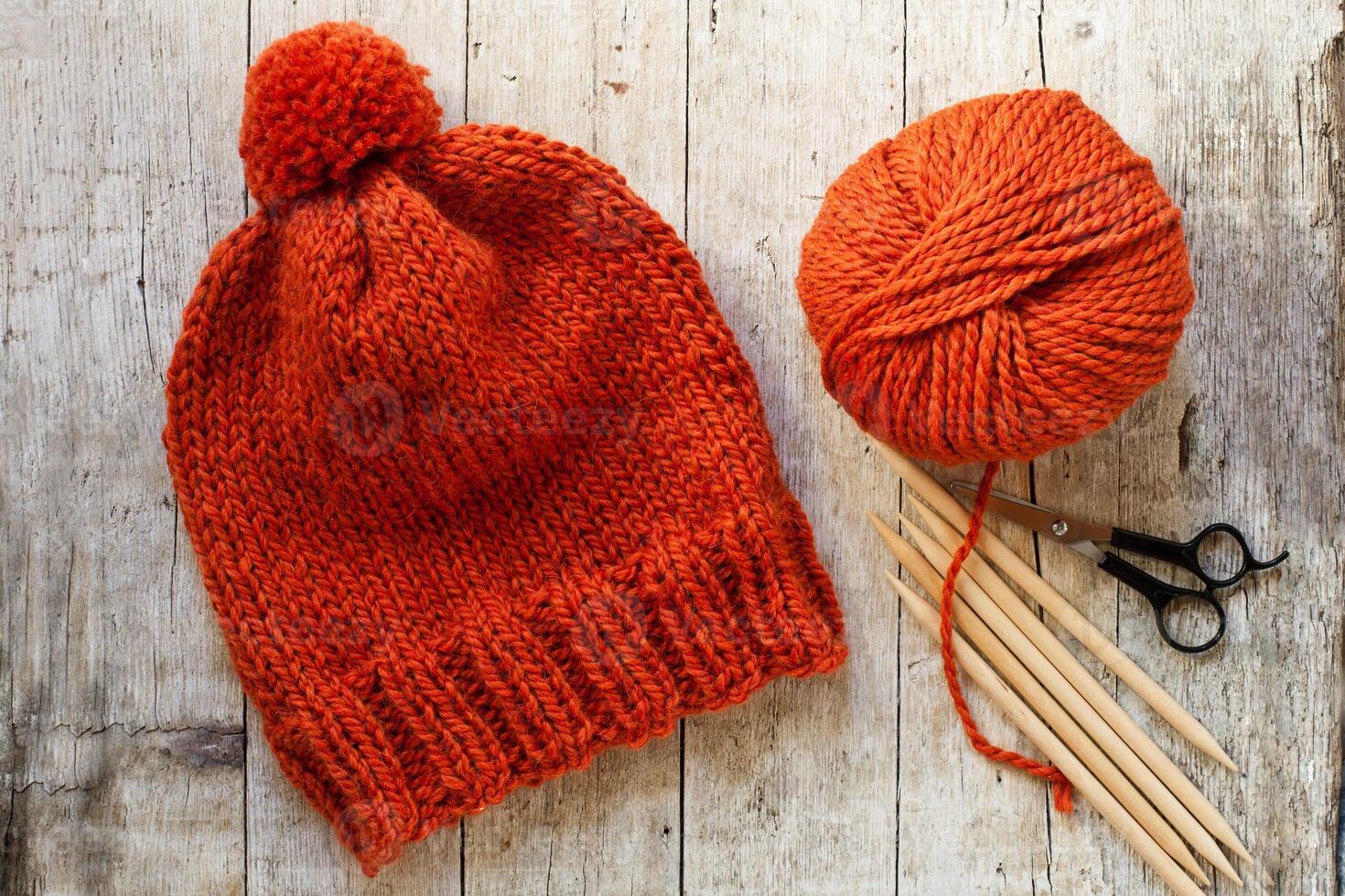wool orange hat, knitting needles and yarn photo